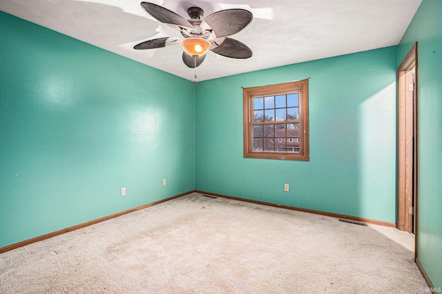 carpeted spare room featuring a ceiling fan, visible vents, and baseboards