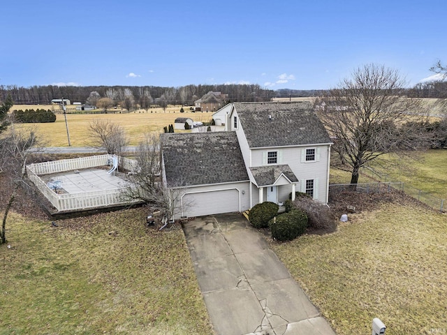 view of front of property with driveway, a garage, roof with shingles, fence, and a front yard