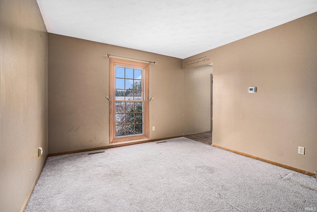 spare room with carpet flooring, visible vents, and baseboards