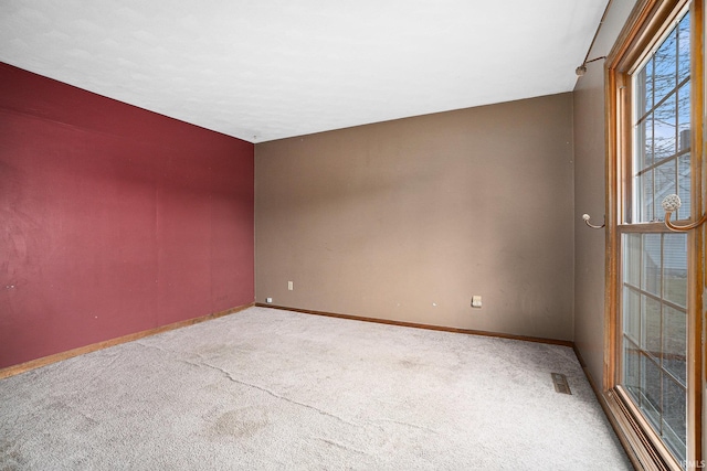 unfurnished room with carpet floors, visible vents, and baseboards