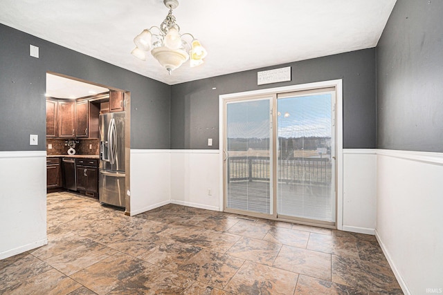 unfurnished dining area featuring baseboards and an inviting chandelier