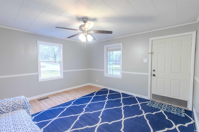 foyer entrance with plenty of natural light, visible vents, wood finished floors, and ornamental molding