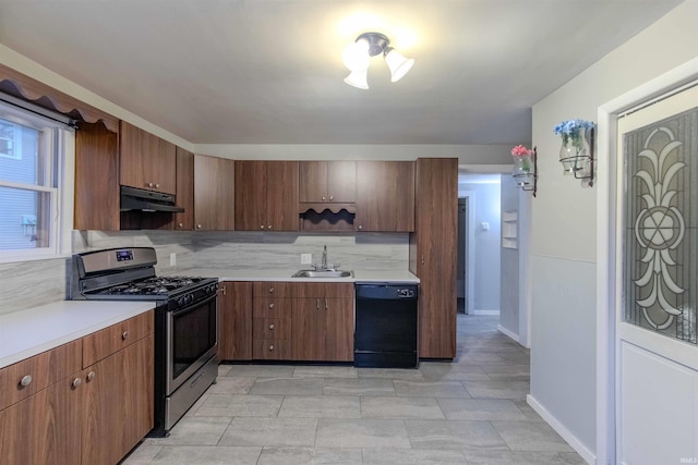 kitchen with under cabinet range hood, a sink, black dishwasher, light countertops, and stainless steel range with gas stovetop