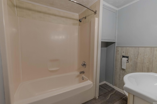 bathroom featuring shower / bath combination, a wainscoted wall, ornamental molding, and a sink