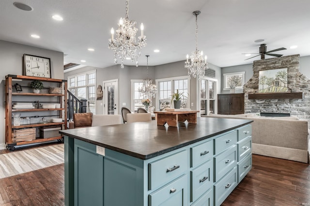 kitchen featuring dark wood-style floors, dark countertops, open floor plan, and a fireplace