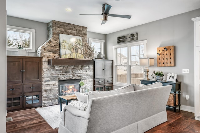 living room with dark wood-style flooring, a fireplace, baseboards, and ceiling fan