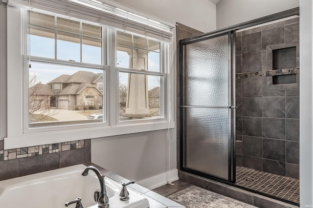 full bathroom with a shower stall, baseboards, and a bath