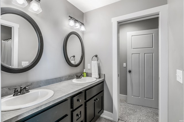 full bathroom featuring double vanity, a sink, and baseboards