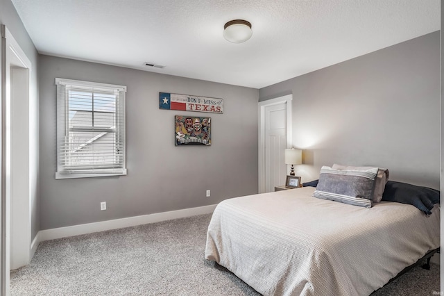 bedroom featuring a textured ceiling, carpet, visible vents, and baseboards