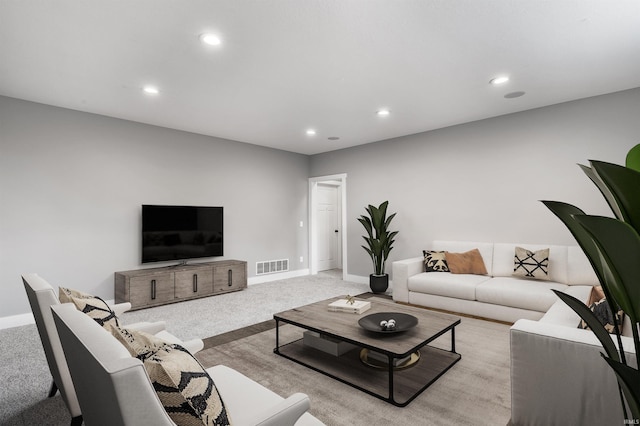 living room with recessed lighting, visible vents, light carpet, and baseboards