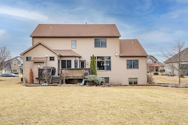 back of property featuring roof with shingles, a yard, and a wooden deck