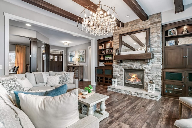 living room featuring built in features, a stone fireplace, wood finished floors, beamed ceiling, and ornate columns