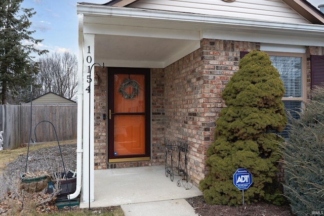 property entrance featuring fence and brick siding