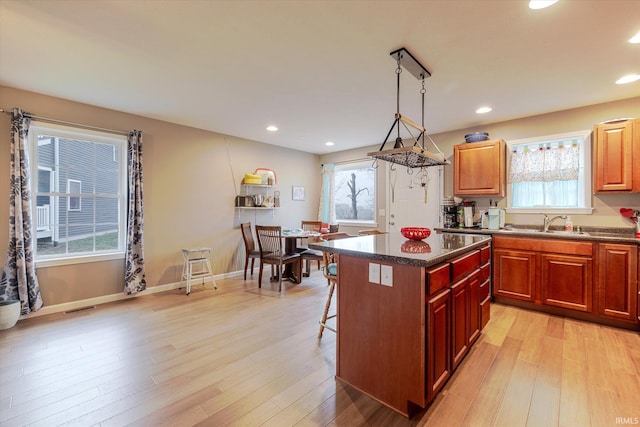 kitchen with a breakfast bar, a center island, light wood finished floors, visible vents, and a sink