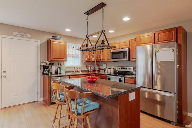 kitchen with appliances with stainless steel finishes, a kitchen breakfast bar, a center island, light wood-style floors, and recessed lighting