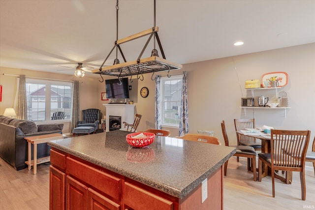 kitchen featuring dark countertops, a fireplace, a kitchen island, and dark brown cabinets