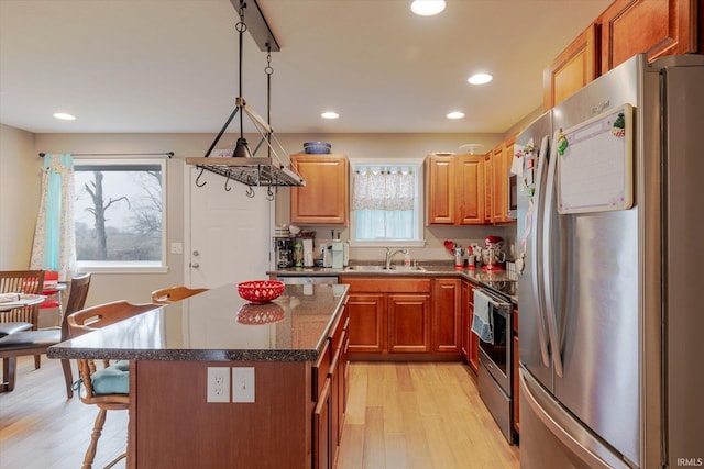 kitchen with light wood finished floors, appliances with stainless steel finishes, plenty of natural light, and a sink