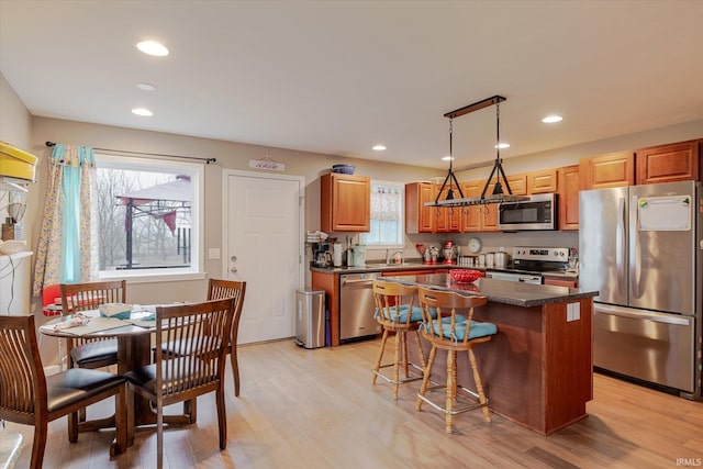 kitchen with dark countertops, light wood-style flooring, a kitchen island, stainless steel appliances, and recessed lighting