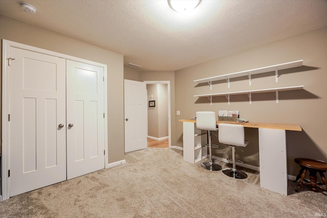 office space featuring a textured ceiling, carpet, and baseboards