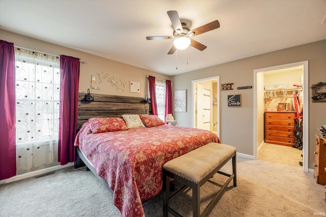 bedroom with light colored carpet, visible vents, baseboards, a spacious closet, and ensuite bath