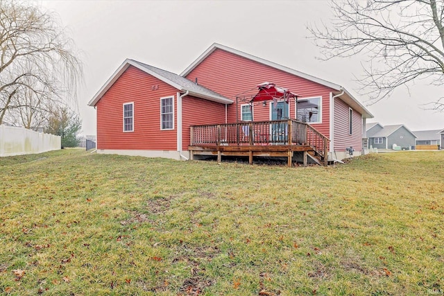 rear view of house with a deck, a yard, and fence