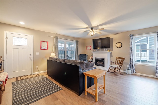 living room with baseboards, a fireplace, visible vents, and light wood finished floors