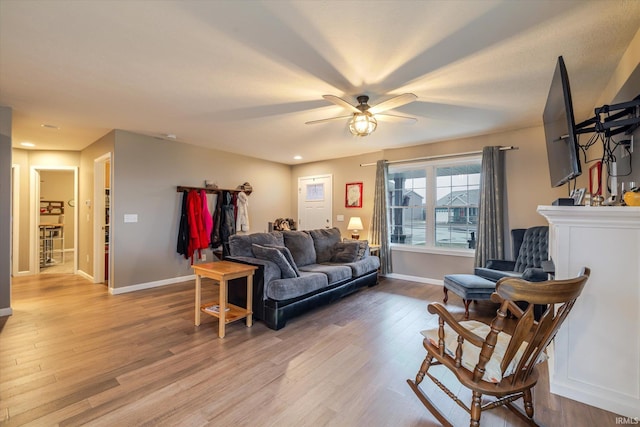 living room with ceiling fan, light wood-style flooring, and baseboards