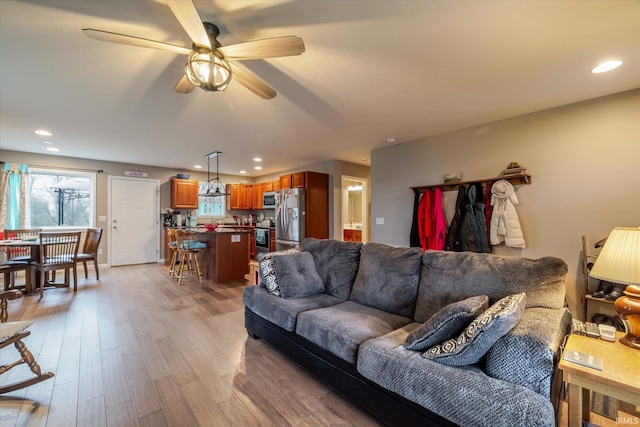 living room featuring light wood-style floors, baseboards, a ceiling fan, and recessed lighting