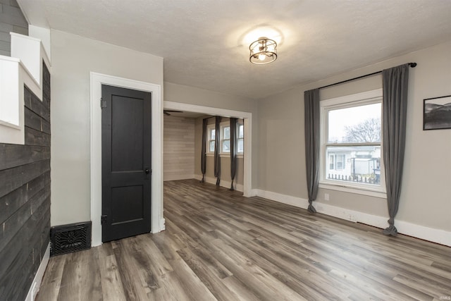 empty room featuring a textured ceiling, baseboards, and wood finished floors