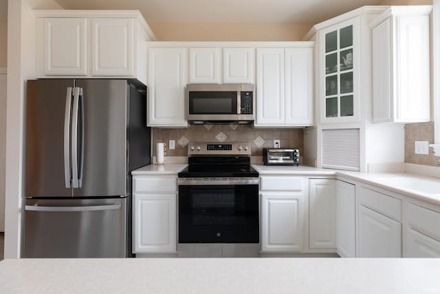 kitchen featuring appliances with stainless steel finishes, white cabinetry, and backsplash