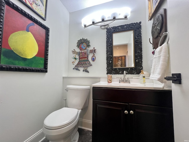 half bathroom featuring toilet, baseboards, and vanity