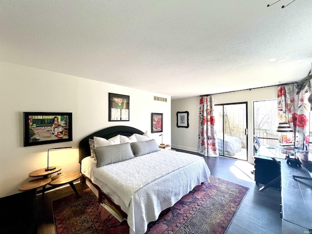 bedroom featuring access to outside, a textured ceiling, visible vents, and wood finished floors