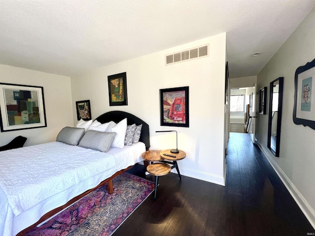 bedroom with visible vents, dark wood finished floors, a textured ceiling, and baseboards