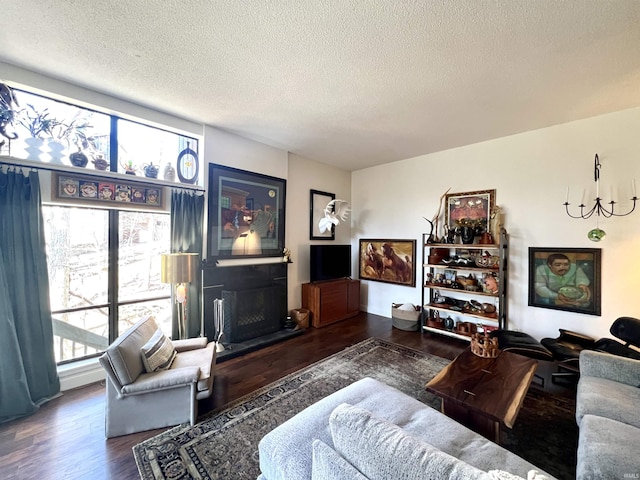 living room with a fireplace, a textured ceiling, and wood finished floors