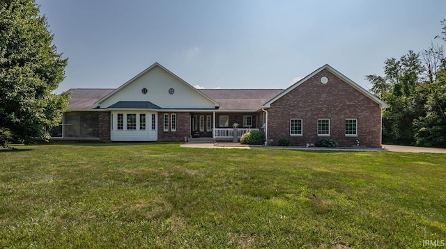 view of front of property with covered porch, brick siding, and a front yard