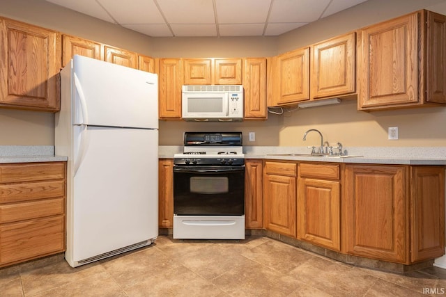 kitchen with light countertops, white appliances, a drop ceiling, and a sink