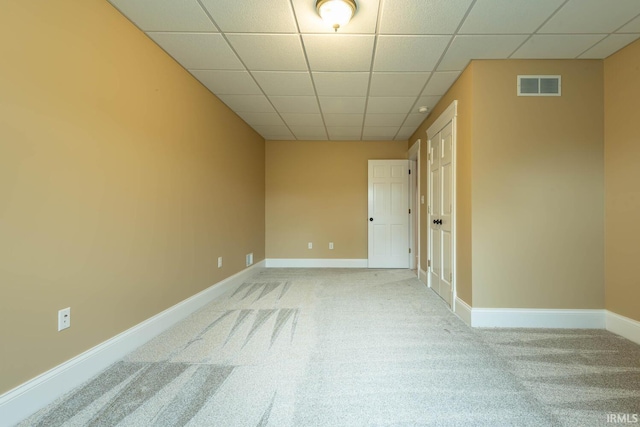 carpeted empty room featuring a paneled ceiling, visible vents, and baseboards