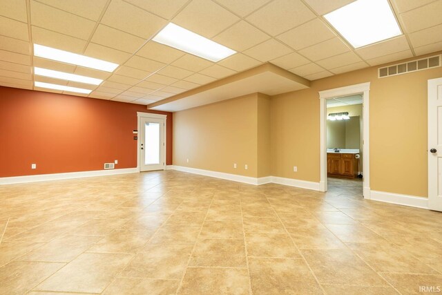 spare room with baseboards, visible vents, and a drop ceiling