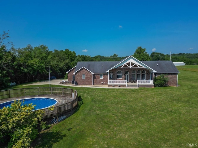 back of property with brick siding, a lawn, and a fenced in pool