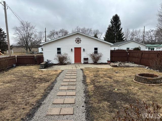 view of front of home with a fenced backyard and a fire pit