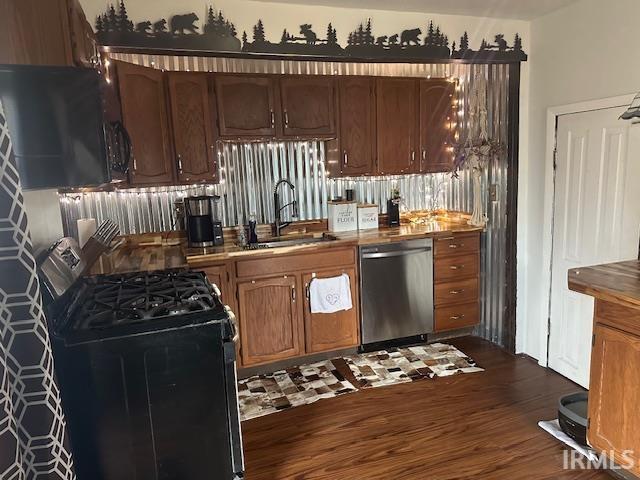 kitchen featuring dark wood-style flooring, a sink, black gas range oven, and stainless steel dishwasher