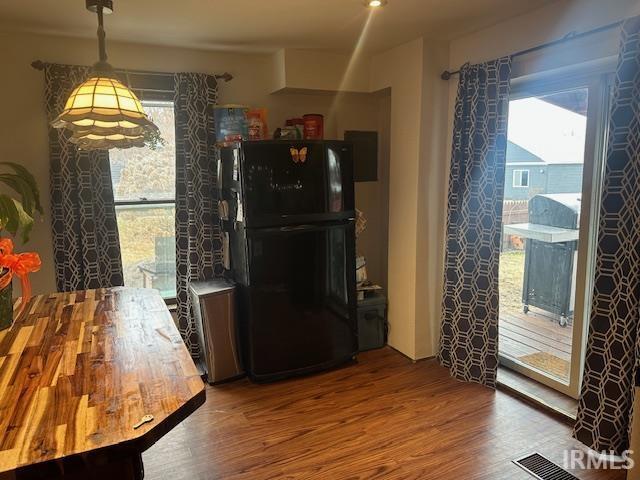 kitchen with freestanding refrigerator, visible vents, and wood finished floors