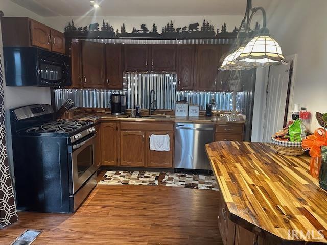 kitchen featuring visible vents, butcher block counters, appliances with stainless steel finishes, wood finished floors, and a sink