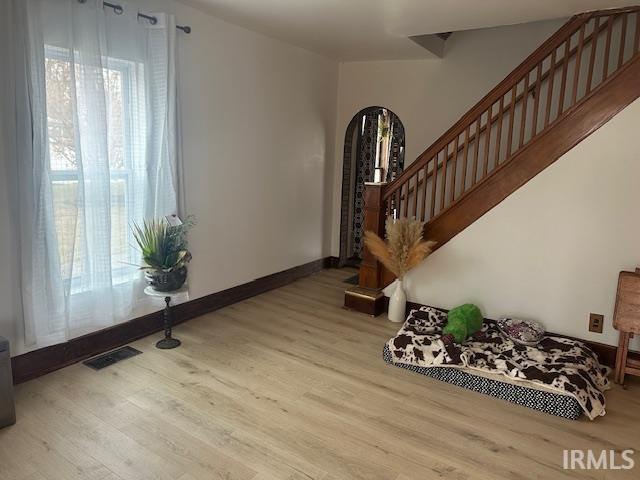 entrance foyer featuring arched walkways, wood finished floors, visible vents, baseboards, and stairs