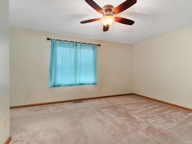 unfurnished room with a textured ceiling, a ceiling fan, visible vents, baseboards, and carpet