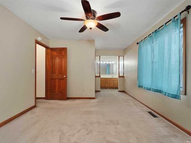 unfurnished bedroom with light carpet, a textured ceiling, visible vents, and baseboards