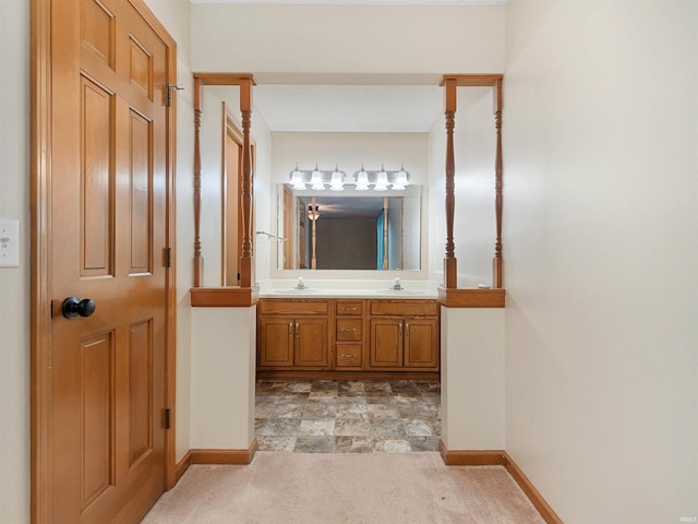 full bath with double vanity, baseboards, and a sink