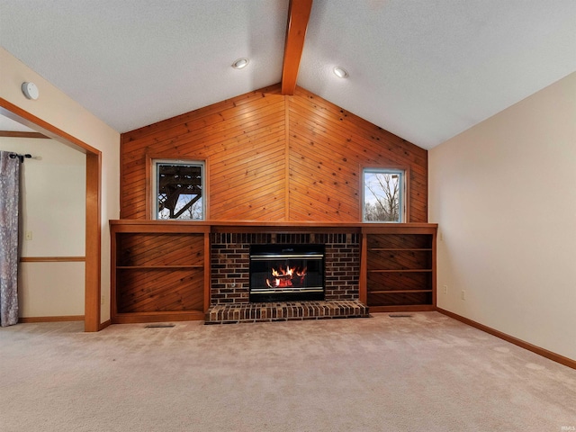 carpeted living area with baseboards, lofted ceiling with beams, a textured ceiling, wood walls, and a brick fireplace