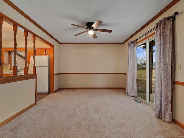 unfurnished room featuring light carpet, visible vents, ornamental molding, and a textured ceiling