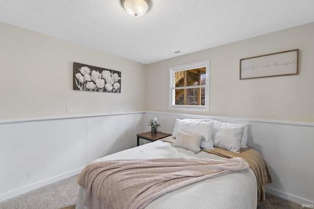 bedroom with carpet floors, visible vents, a textured ceiling, and baseboards